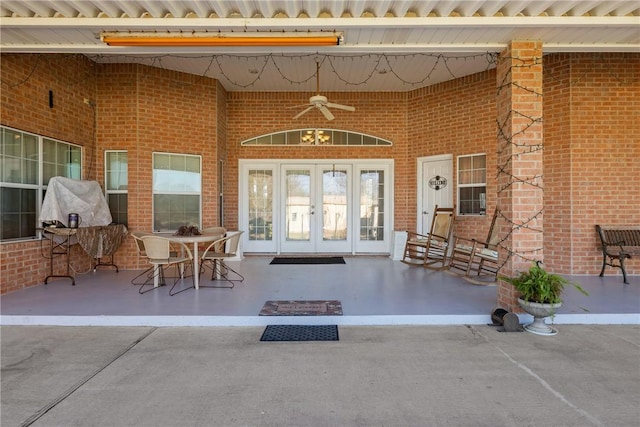 entrance to property featuring brick siding, a patio area, french doors, and ceiling fan