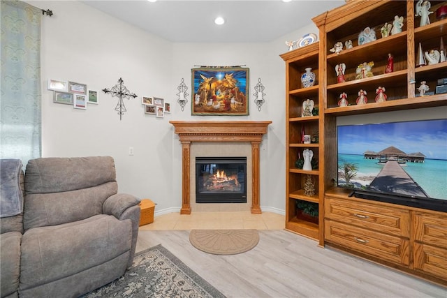 living area featuring a glass covered fireplace, baseboards, and light wood-style floors