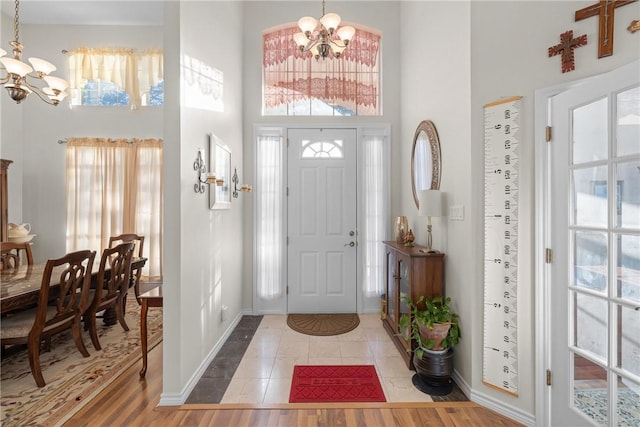 entryway featuring a notable chandelier, a high ceiling, baseboards, and wood finished floors