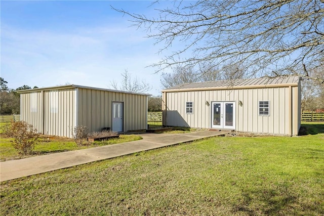 view of outdoor structure featuring an outbuilding, french doors, and fence