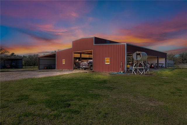 outdoor structure at dusk with an outbuilding, driveway, a yard, and a pole building