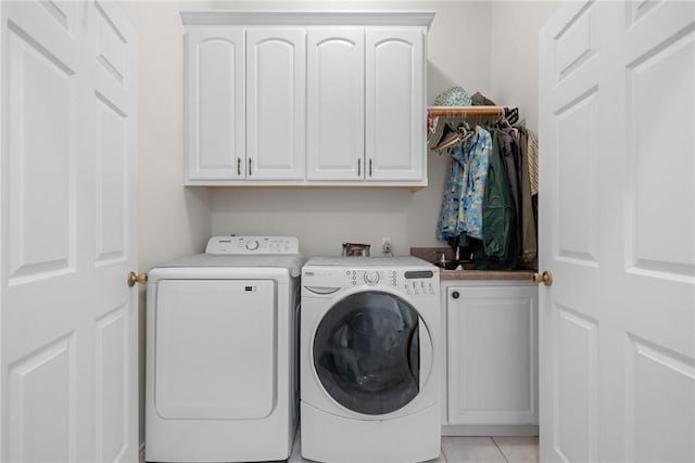 laundry room featuring light tile patterned floors, cabinet space, and washer and dryer