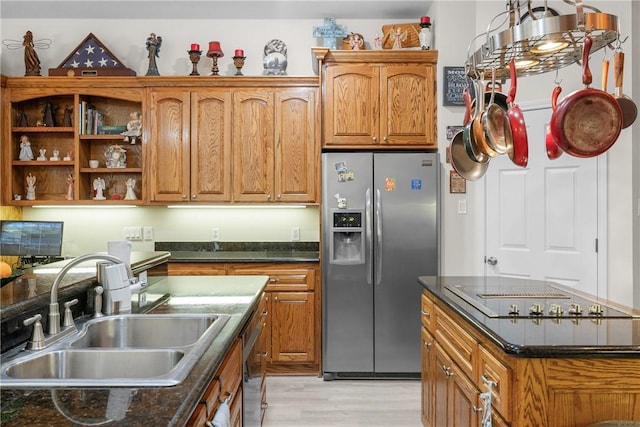 kitchen featuring a center island, light wood-style flooring, brown cabinetry, stainless steel appliances, and a sink