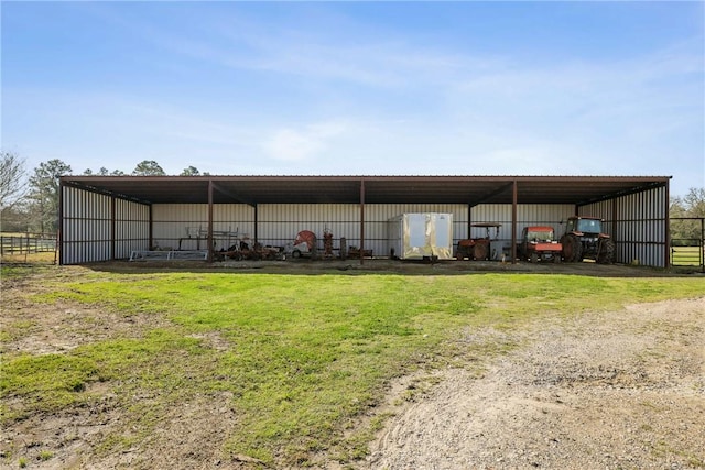 view of pole building with a carport, driveway, a yard, and fence