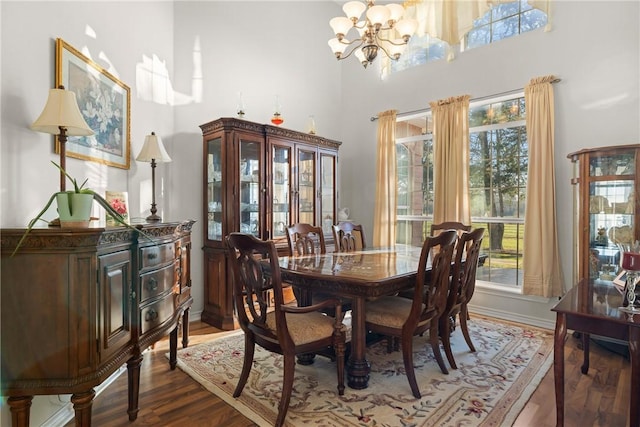 dining space with a high ceiling, wood finished floors, baseboards, and a chandelier