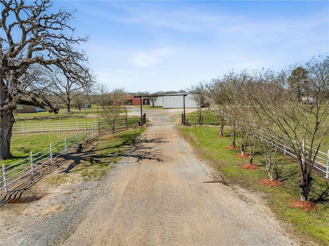 view of street with a gated entry, a rural view, and dirt driveway