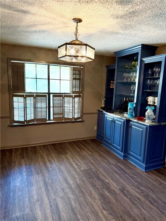 67 Fairway Dr, Hilltop Lakes, TX 77871 - indoor bar with dark wood-style flooring, a textured ceiling, and hanging light fixtures