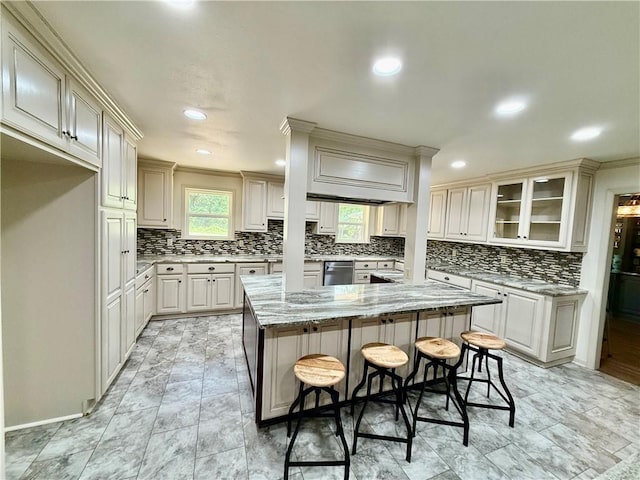 67 Fairway Dr, Hilltop Lakes, TX 77871 - kitchen with a breakfast bar area, backsplash, a kitchen island, light stone countertops, and glass insert cabinets