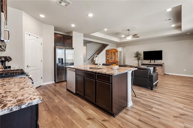 6317 Daytona Dr, College Station, TX 77845 - kitchen with visible vents, a ceiling fan, appliances with stainless steel finishes, a sink, and a tray ceiling