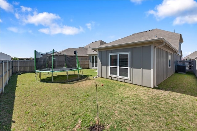 6317 Daytona Dr, College Station, TX 77845 - rear view of property with a trampoline, board and batten siding, a fenced backyard, and a lawn