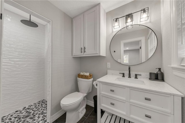 bathroom featuring tile patterned flooring, a tile shower, vanity, and toilet