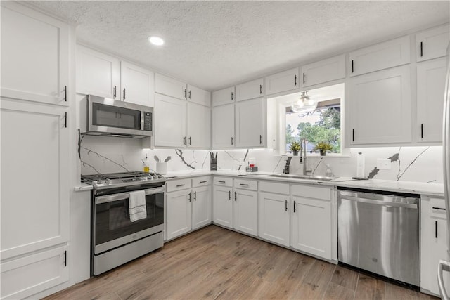 kitchen featuring white cabinetry, sink, light wood-type flooring, and appliances with stainless steel finishes