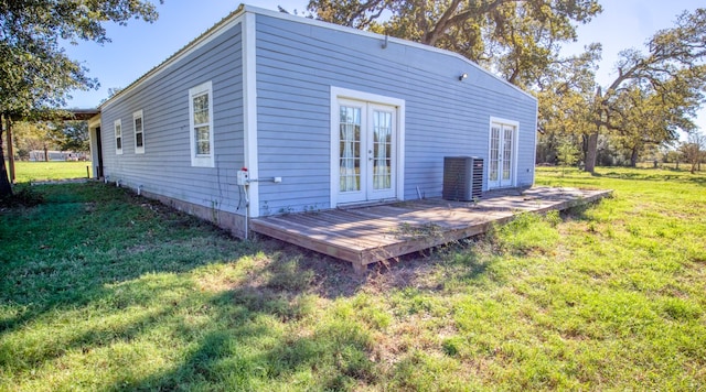 back of property with cooling unit, a lawn, french doors, and a deck