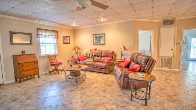 living room featuring a drop ceiling, light tile patterned floors, ornamental molding, and ceiling fan