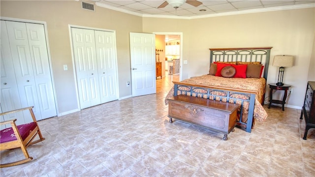 bedroom with crown molding, ceiling fan, and two closets