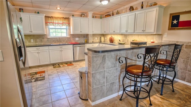 kitchen with sink, a breakfast bar area, white cabinetry, appliances with stainless steel finishes, and kitchen peninsula