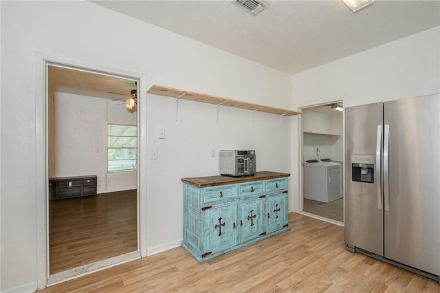 202 S Broadway St, Caldwell, TX 77836 - kitchen with stainless steel fridge with ice dispenser, wooden counters, open shelves, blue cabinetry, and washing machine and clothes dryer