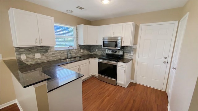 kitchen featuring white cabinetry, sink, stainless steel appliances, kitchen peninsula, and hardwood / wood-style floors