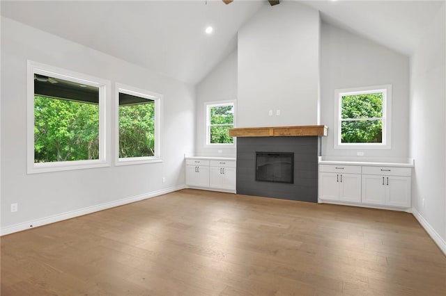 13291 Hopes Creek Rd, College Station, TX 77845 - unfurnished living room featuring a glass covered fireplace, baseboards, high vaulted ceiling, light wood-type flooring, and ceiling fan