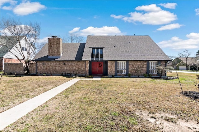 view of front of property with a front yard, brick siding, a chimney, and roof with shingles