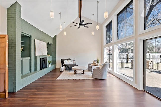 sitting room featuring dark wood-style flooring, beam ceiling, a fireplace, a ceiling fan, and high vaulted ceiling