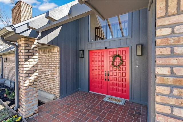 entrance to property with a chimney and brick siding