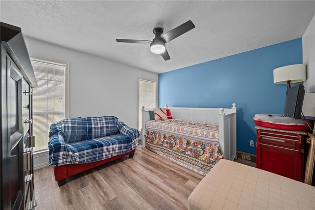 bedroom featuring ceiling fan, wood finished floors, baseboards, and a textured ceiling