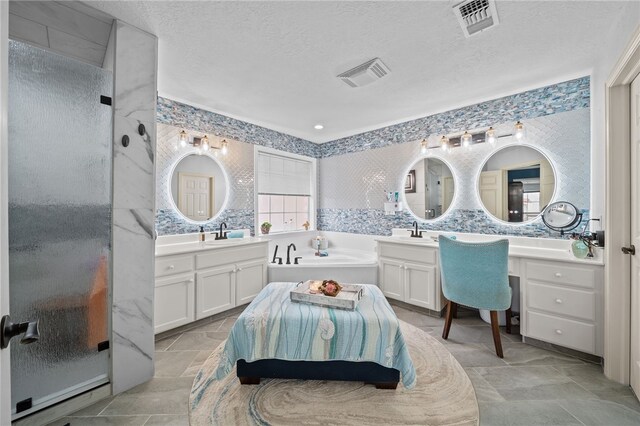 full bathroom with a textured ceiling, visible vents, and a sink