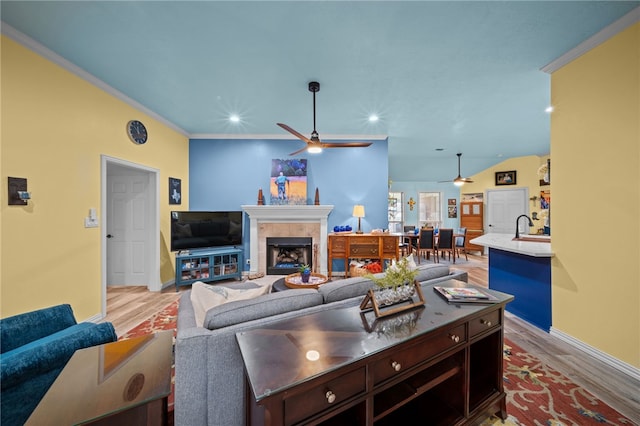 living area featuring crown molding, recessed lighting, a fireplace, wood finished floors, and a ceiling fan