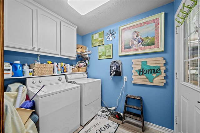 laundry room featuring a textured ceiling, cabinet space, separate washer and dryer, light wood finished floors, and baseboards