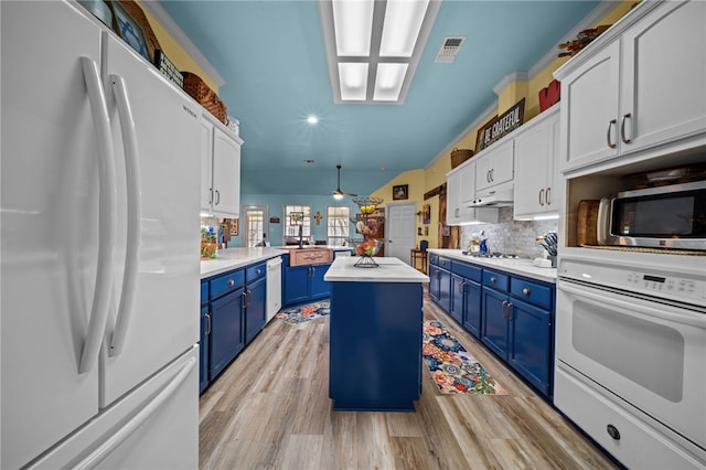 kitchen with blue cabinets, light wood-style flooring, a center island, white appliances, and a peninsula