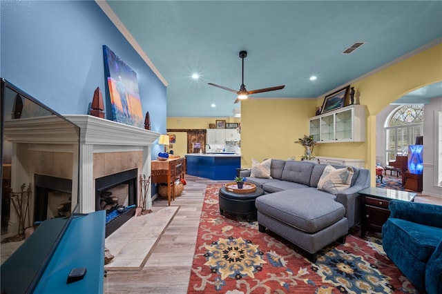 living room featuring crown molding, a fireplace, visible vents, and arched walkways