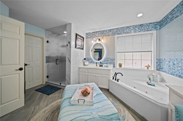 full bathroom with vanity, a stall shower, a whirlpool tub, a textured ceiling, and tile walls