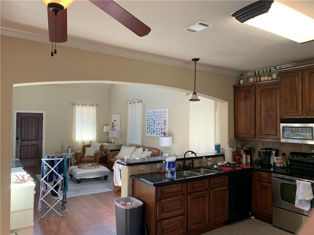 kitchen with kitchen peninsula, appliances with stainless steel finishes, ceiling fan, sink, and hardwood / wood-style floors