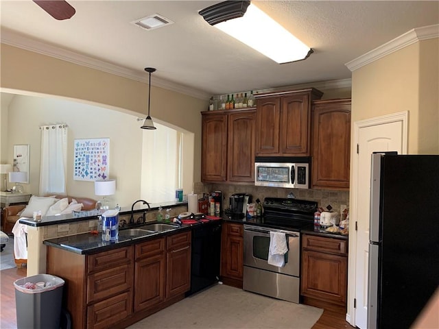 kitchen with kitchen peninsula, appliances with stainless steel finishes, ornamental molding, and sink