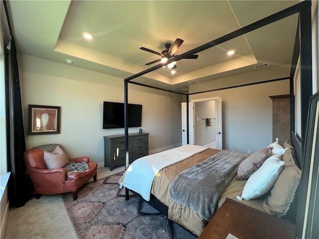 bedroom with carpet, a raised ceiling, and ceiling fan