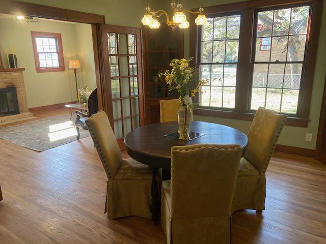 dining area with a brick fireplace, hardwood / wood-style flooring, and an inviting chandelier