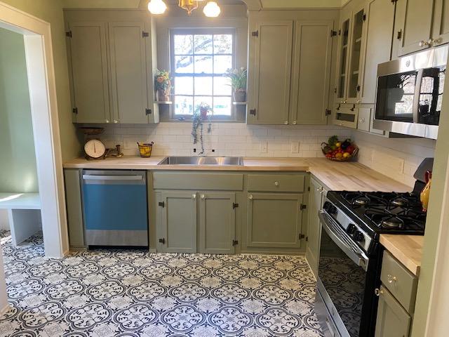 kitchen with sink, backsplash, a notable chandelier, and stainless steel appliances