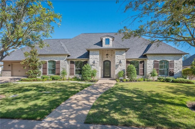 french country home featuring a front lawn and a garage