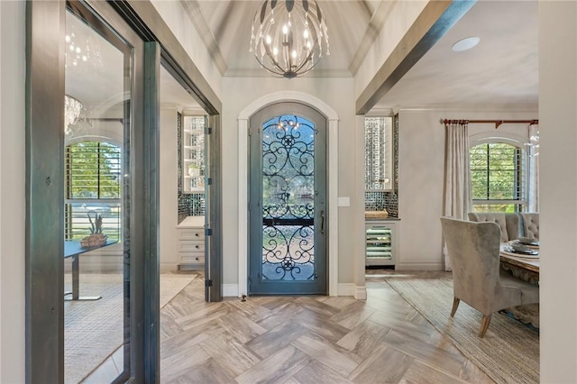 entrance foyer with wine cooler, light parquet floors, a chandelier, and ornamental molding