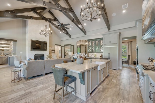 kitchen with light stone countertops, sink, high vaulted ceiling, a spacious island, and a fireplace