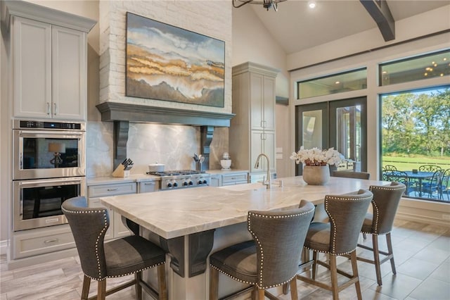 kitchen featuring light stone countertops, stainless steel appliances, a kitchen breakfast bar, backsplash, and light hardwood / wood-style floors