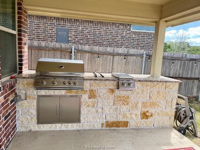 view of patio featuring fence, an outdoor kitchen, and area for grilling