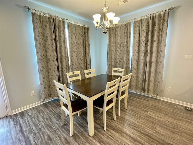 unfurnished dining area with baseboards, visible vents, a chandelier, and wood finished floors