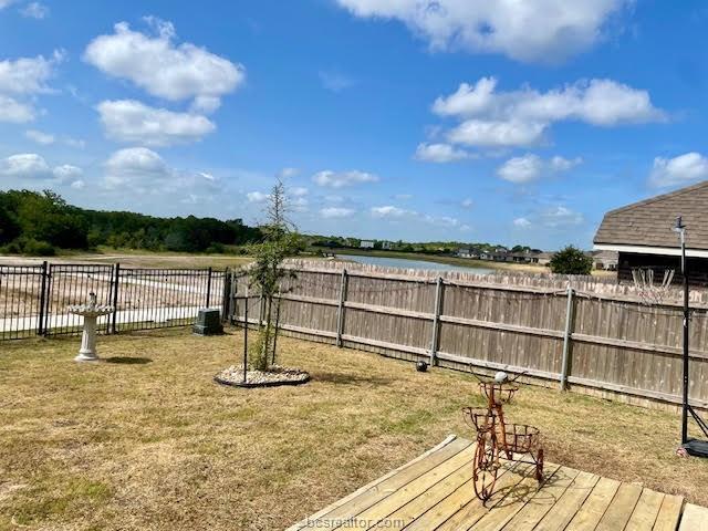 view of yard with fence and a deck with water view