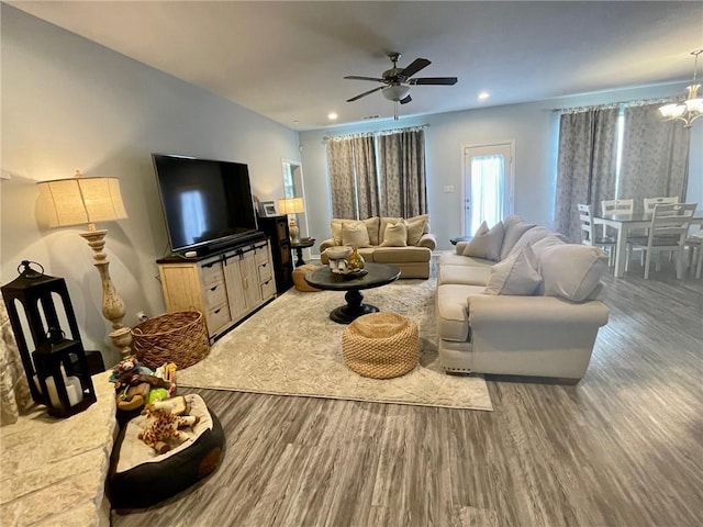 living area with ceiling fan with notable chandelier, wood finished floors, and recessed lighting