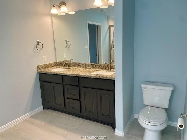 full bathroom featuring baseboards, a sink, toilet, and double vanity