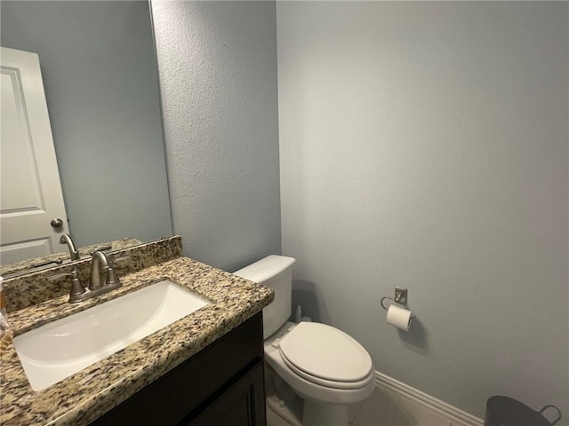 half bath featuring vanity, toilet, and baseboards