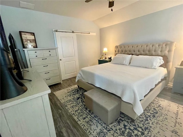 bedroom with vaulted ceiling, ceiling fan, a barn door, and wood finished floors