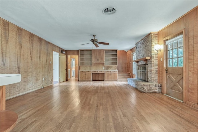 1500 Galde St, College Station, TX 77840 - unfurnished living room featuring a fireplace, light wood-style flooring, a ceiling fan, and wooden walls